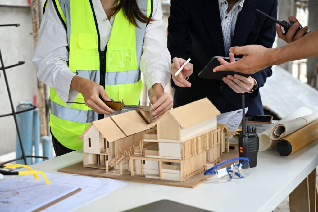 engineers and businessman examining blueprints at table with architectural models in the foreground