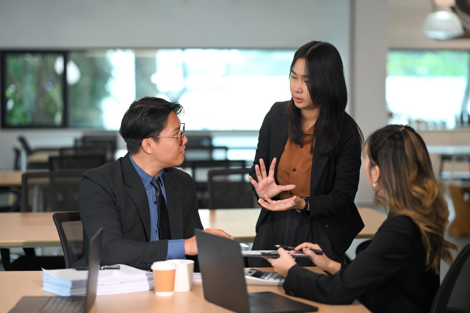 female team leader explaining project strategy to colleagues in a modern meeting room
