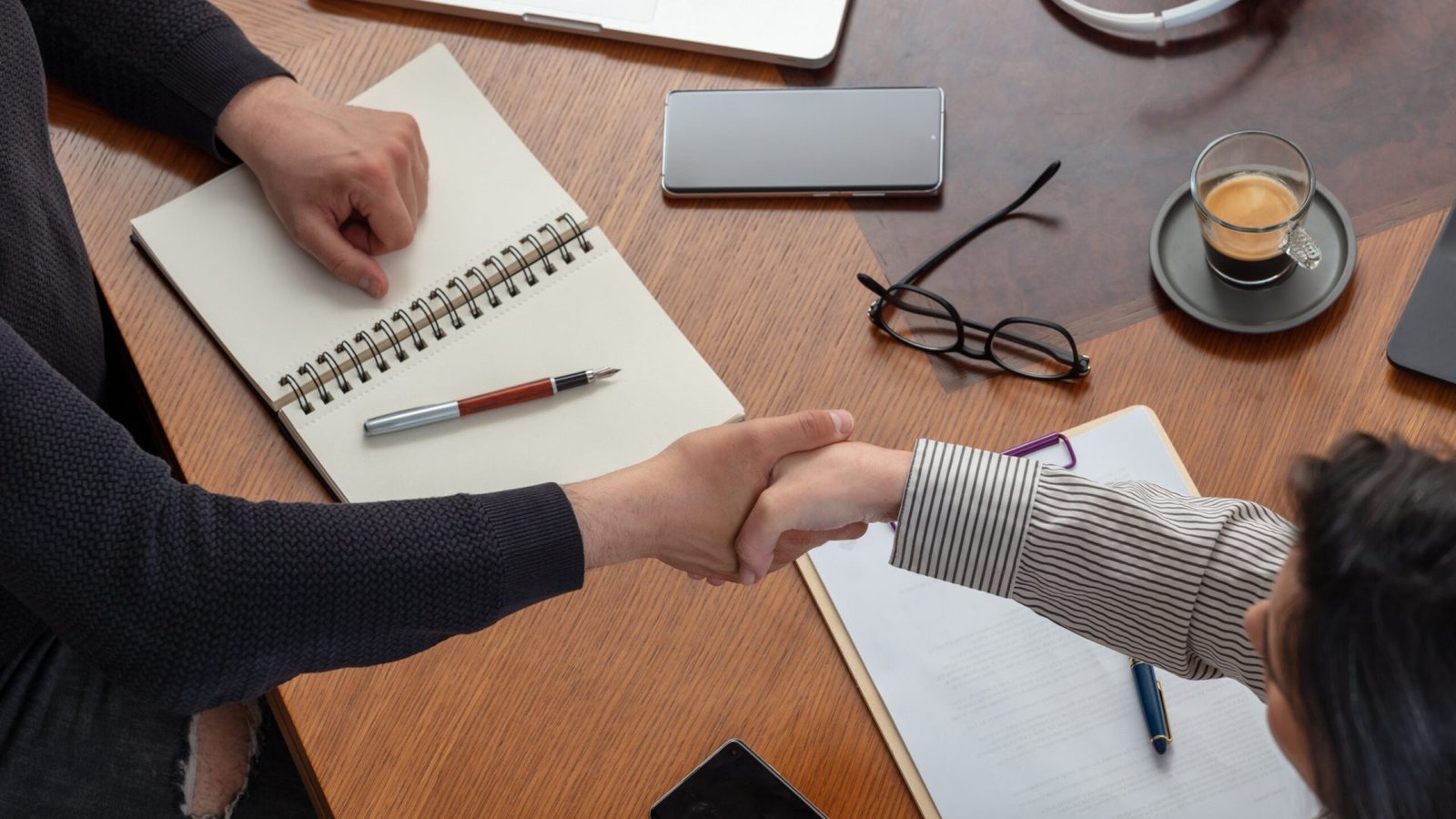 business handshake, deal success. two young people at the office table, overhead view